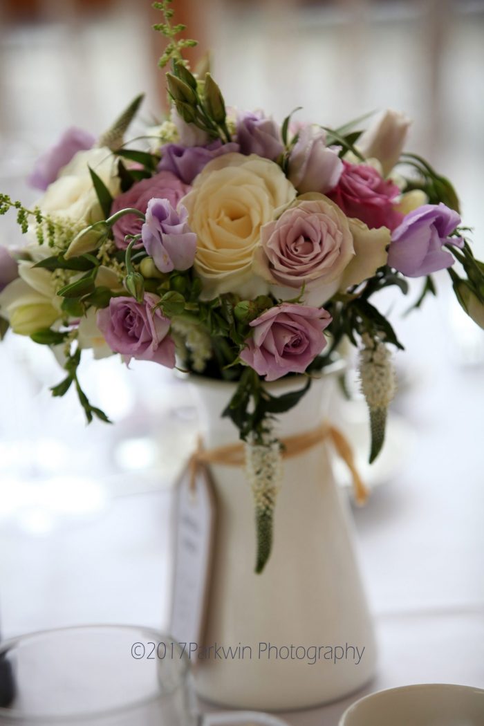 Flowers in cream jug on wedding breakfast table at Fanhams Hall